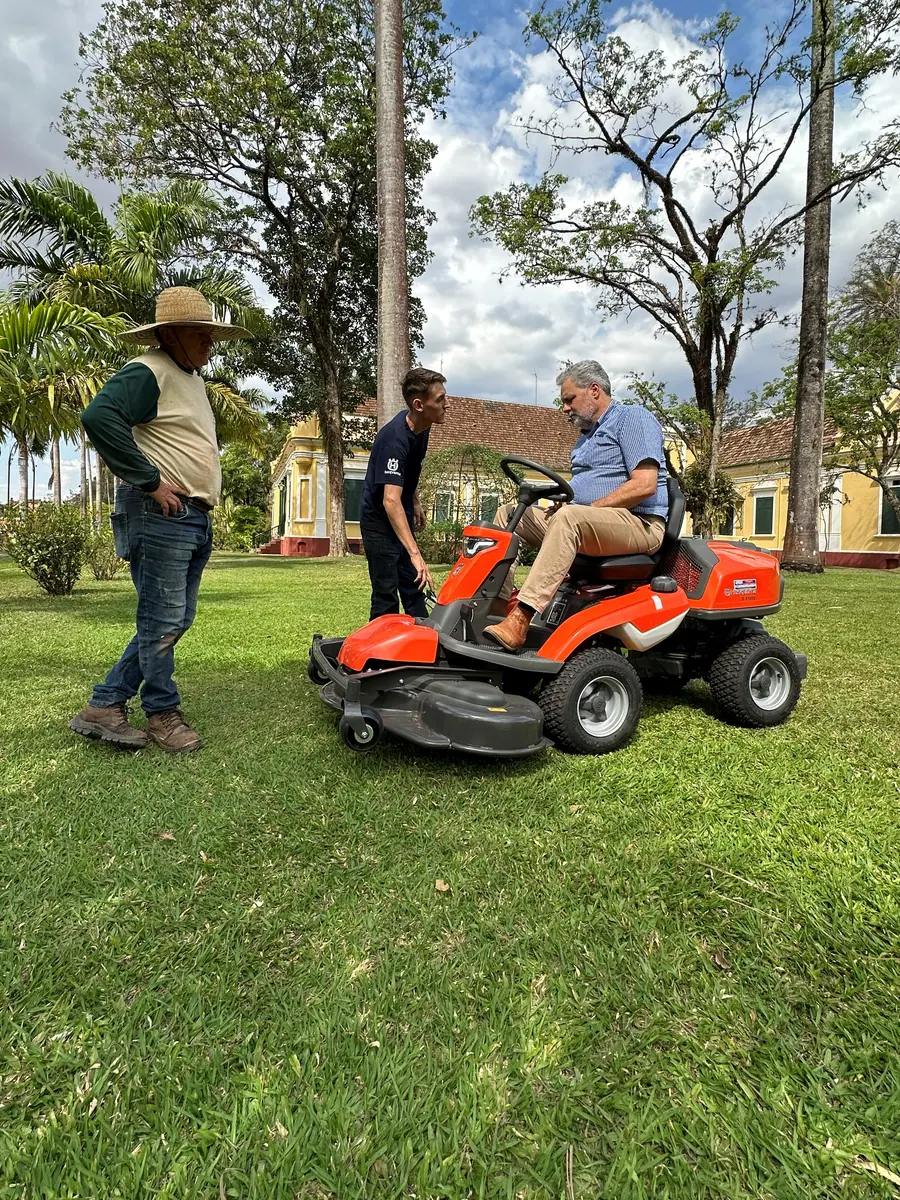 Equipe da Vardão apresentando um Rider Husqvarna ao cliente, no jardim de uma fazenda histórica