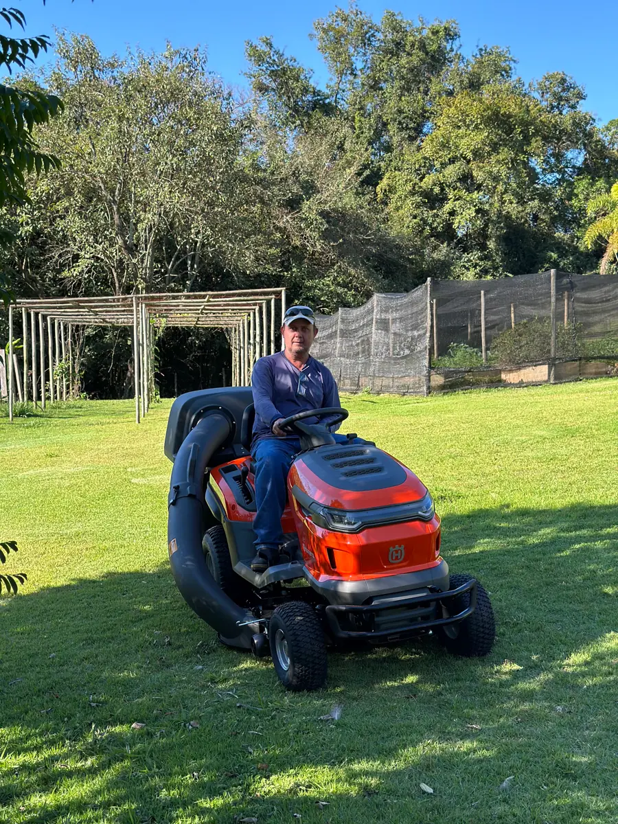 Cliente no trator cortador Husqvarna, no jardim de casa